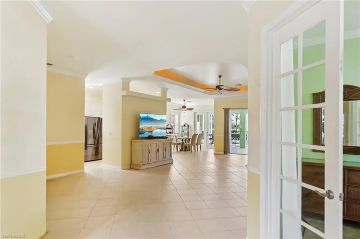 Living area featuring crown molding, light tile patterned floors, a ceiling fan, french doors, and a tray ceiling
