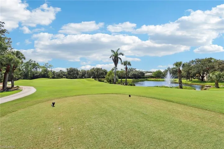 Surrounding community featuring a water view, view of golf course, a lawn, and view of wooded area