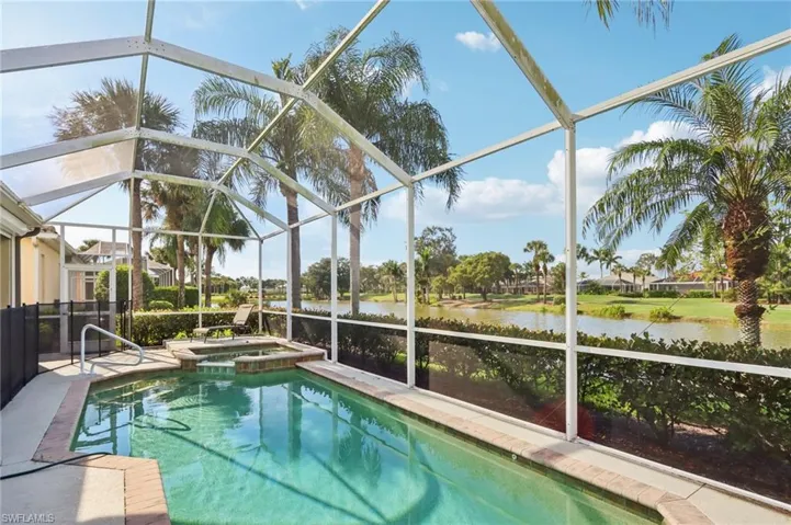 View of swimming pool featuring a lanai, a sunroom, a pool with connected hot tub, and a water view