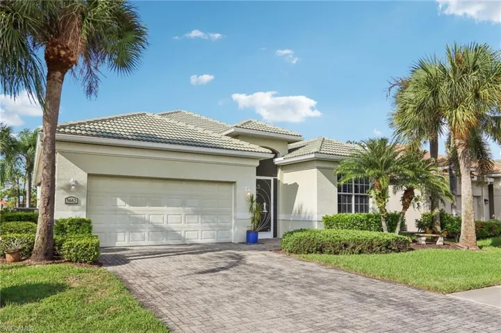View of front of home with a tile roof, decorative driveway, stucco siding, and a garage