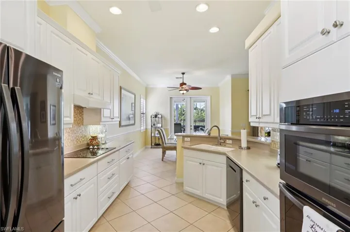 Kitchen with appliances with stainless steel finishes, crown molding, a peninsula, light countertops, and backsplash