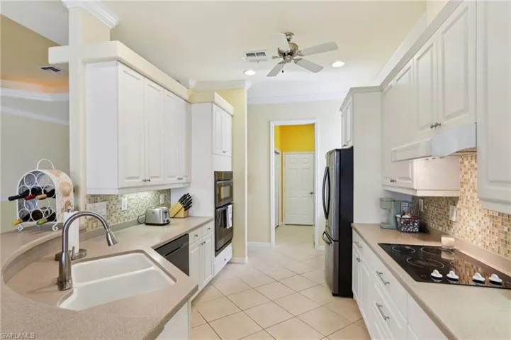 Kitchen featuring decorative backsplash, white cabinetry, ornamental molding, black appliances, and recessed lighting