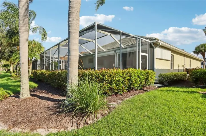 View of home's exterior with a sunroom, a lawn, a lanai, and stucco siding