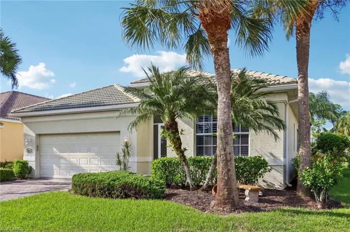 View of front of property featuring a tiled roof, an attached garage, stucco siding, and driveway