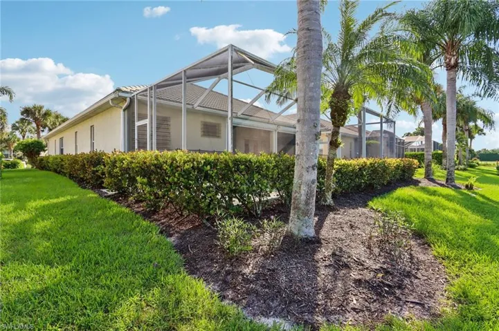 View of side of property with a sunroom, a lawn, stucco siding, and glass enclosure
