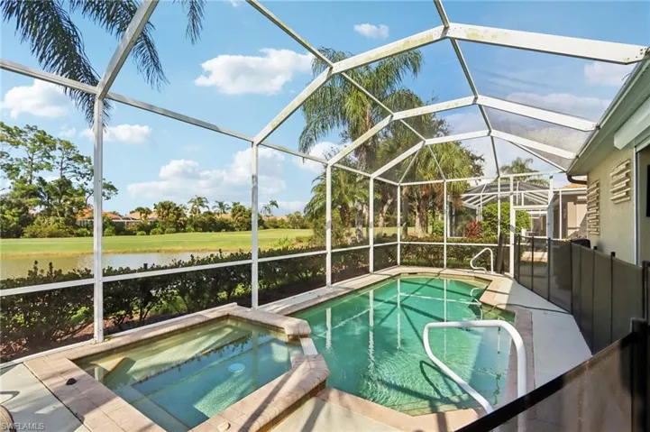 View of pool with a lanai, a sunroom, a pool with connected hot tub, and a water view