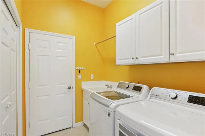 Laundry room featuring light tile patterned flooring, cabinet space, and independent washer and dryer
