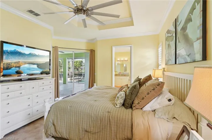 Bedroom featuring access to outside, ornamental molding, a ceiling fan, connected bathroom, and a raised ceiling