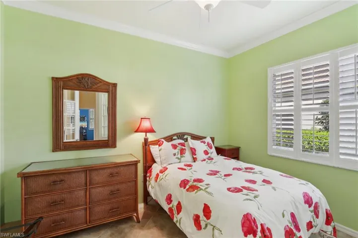 Bedroom with tile patterned flooring, crown molding, and ceiling fan