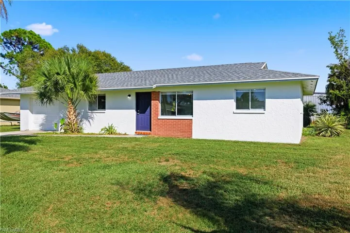 Single story home featuring roof with shingles, stucco siding, a garage, and brick siding
