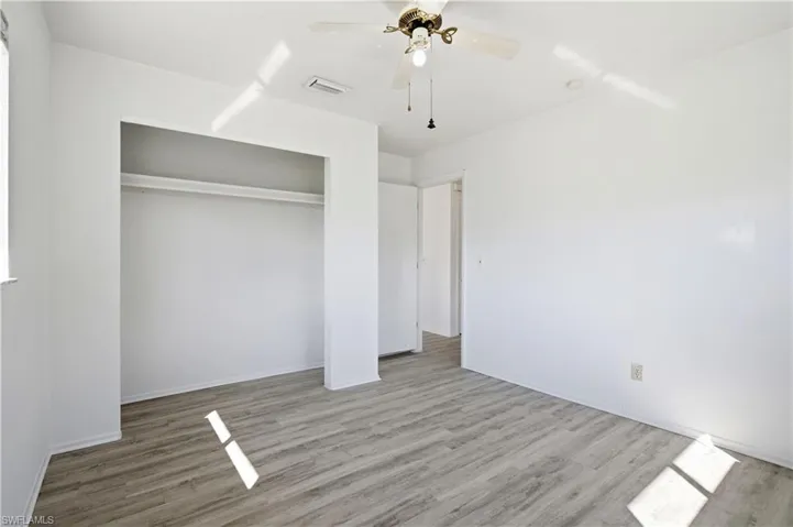 Unfurnished bedroom with wood finished floors, a ceiling fan, and a closet