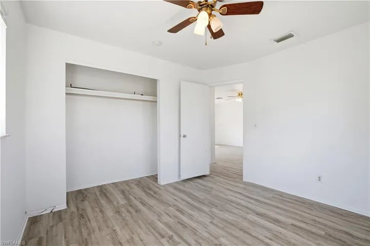 Unfurnished bedroom featuring light wood-style flooring, ceiling fan, and a closet