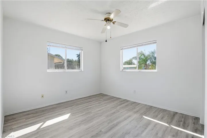 Spare room featuring light wood finished floors, a textured ceiling, and ceiling fan