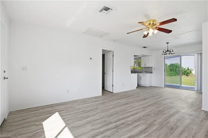 Unfurnished living room with light wood-style flooring, a ceiling fan, and attic access