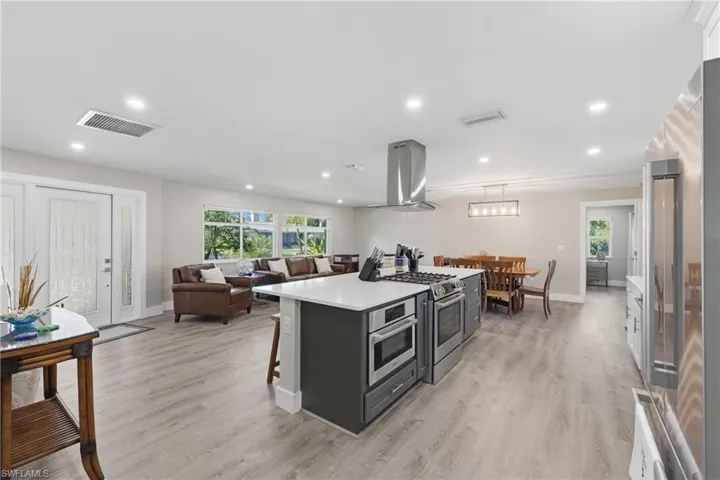 Kitchen with stainless steel appliances, a breakfast bar, a center island, LVP flooring, and open floor plan