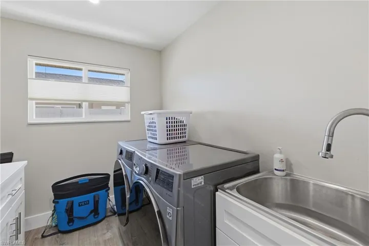 Laundry Room with newer washer and dryer, laundry tub, and cabinets for storage.