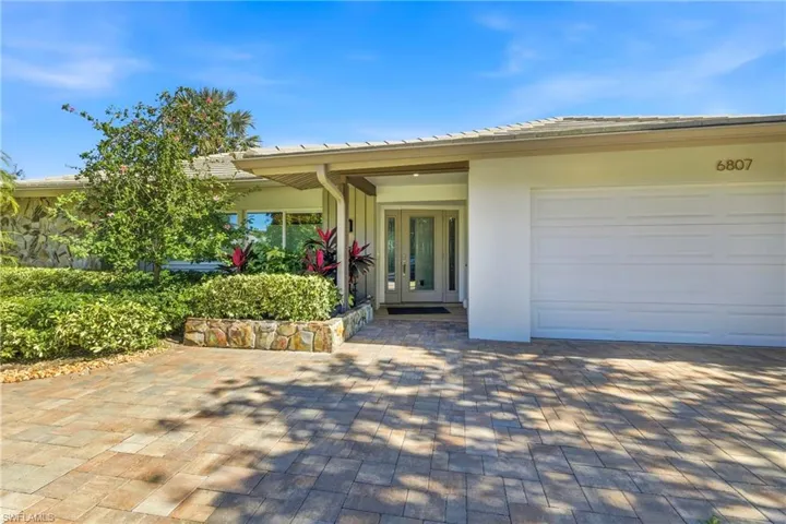 Doorway to property featuring an attached garage, stucco siding, decorative driveway, and french doors
