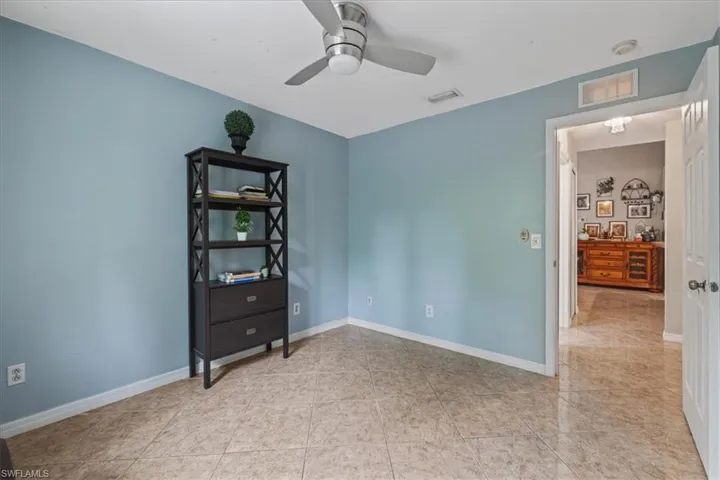 Empty room with a ceiling fan, baseboards, and light tile patterned floors