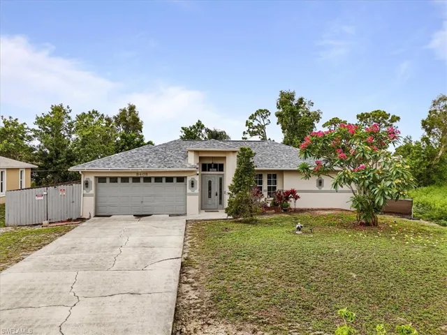 View of front facade with stucco siding, concrete driveway, a front yard, an attached garage, and a shingled roof
