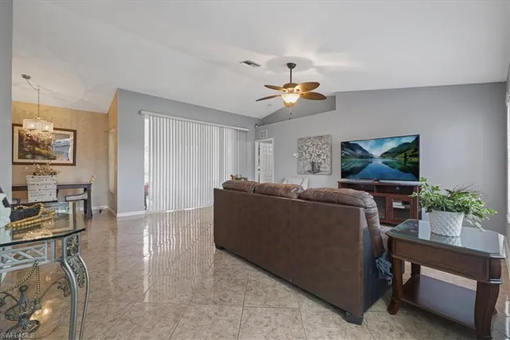 Living room featuring a ceiling fan, baseboards, and vaulted ceiling