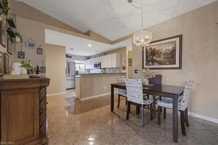 Dining area with lofted ceiling, a chandelier, light tile patterned floors, baseboards, and recessed lighting