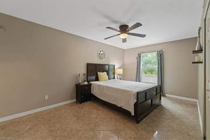 Bedroom with light tile patterned floors, baseboards, and ceiling fan