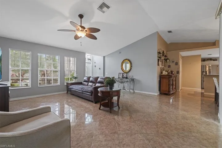 Living room featuring baseboards, a ceiling fan, and lofted ceiling