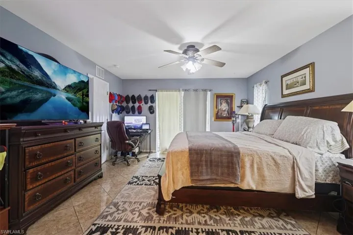 Bedroom featuring light tile patterned flooring, an office area, and ceiling fan