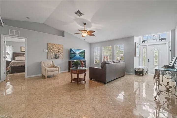 Living room featuring lofted ceiling, a ceiling fan, and baseboards