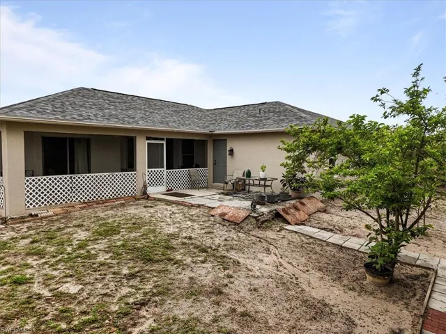 Rear view of property featuring roof with shingles, a patio, and stucco siding