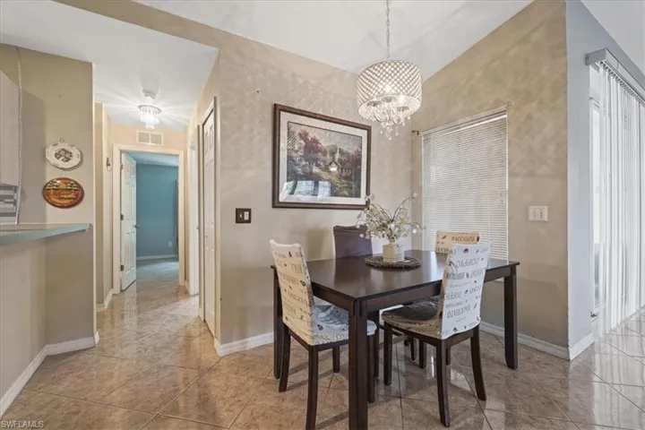 Tiled dining area featuring a chandelier and baseboards
