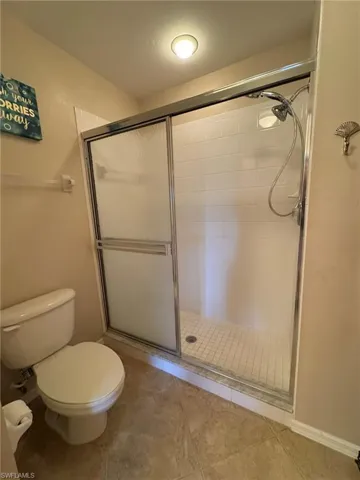 Bathroom with tile patterned flooring, toilet, and a shower with shower door