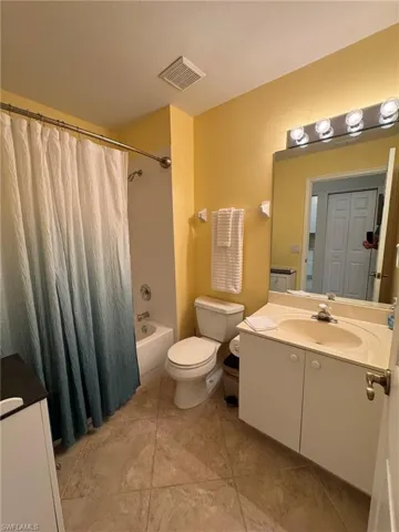 Full bathroom featuring tile patterned flooring, vanity, toilet, and shower / tub combo