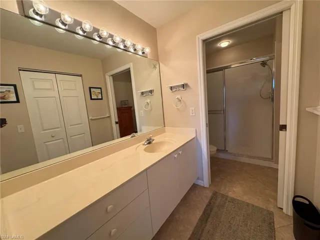 Bathroom featuring toilet, a shower with door, vanity, and tile patterned flooring