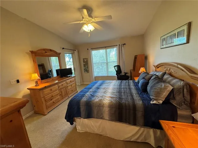 Bedroom featuring ceiling fan, lofted ceiling, and light carpet