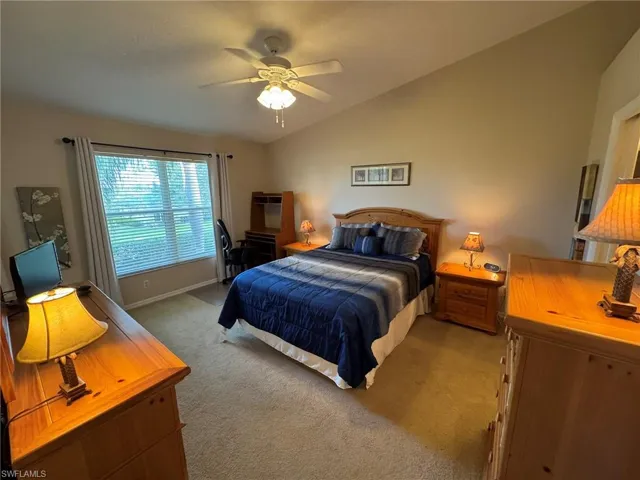 Carpeted bedroom with ceiling fan and lofted ceiling