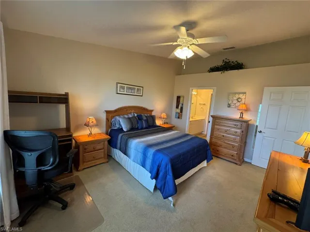 Carpeted bedroom with ensuite bath and ceiling fan