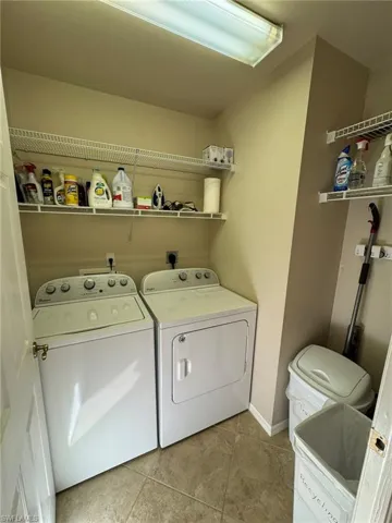 Laundry room with independent washer and dryer and light tile patterned floors