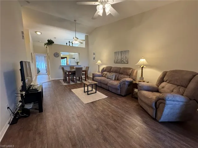 Living room featuring ceiling fan, dark hardwood / wood-style flooring, and lofted ceiling