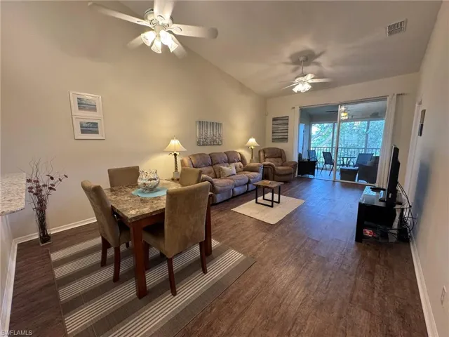 Dining room featuring ceiling fan, dark wood-type flooring, and vaulted ceiling