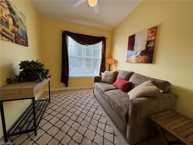 Carpeted living room with vaulted ceiling and ceiling fan