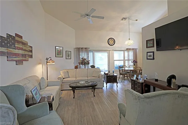 Living room with ceiling fan, wood vinyl  flooring, and high vaulted ceiling