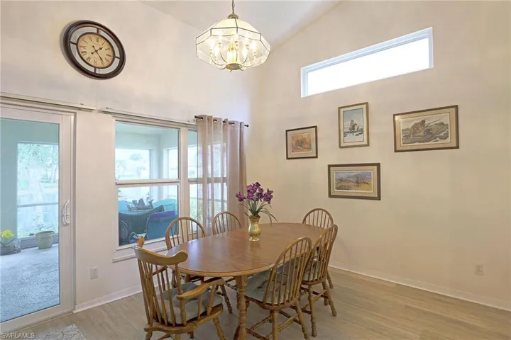 Dining room with a chandelier, light wood finished floors, and high vaulted ceiling