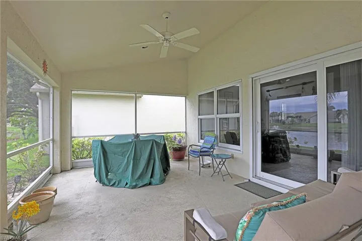 Sunroom with vaulted ceiling, a ceiling fan, and a water view