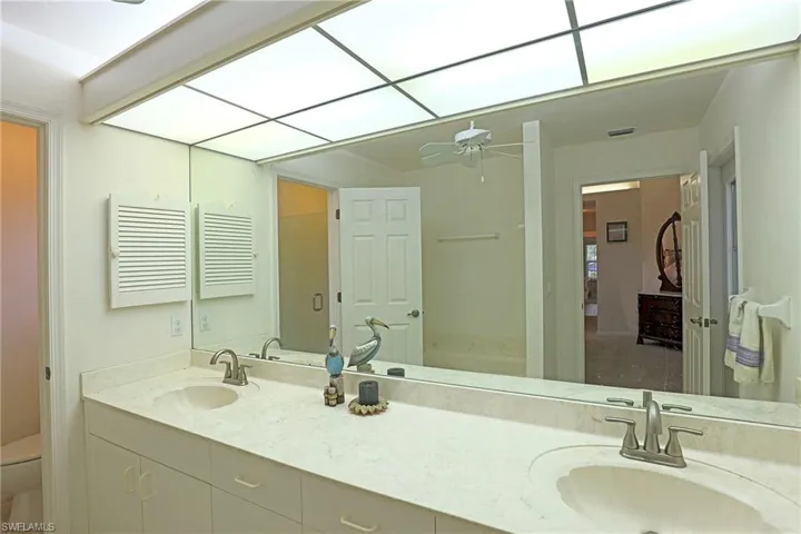 Full bathroom with double vanity, ceiling fan, and a shower