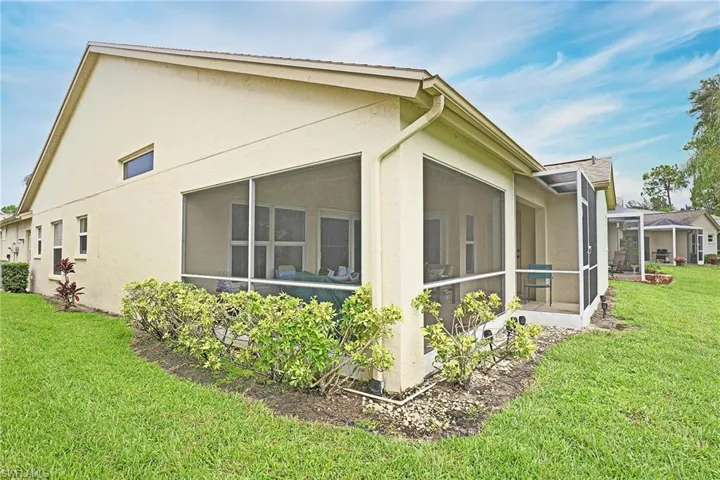 View of property exterior featuring stucco, a lawn, and a sunroom with news screens.
