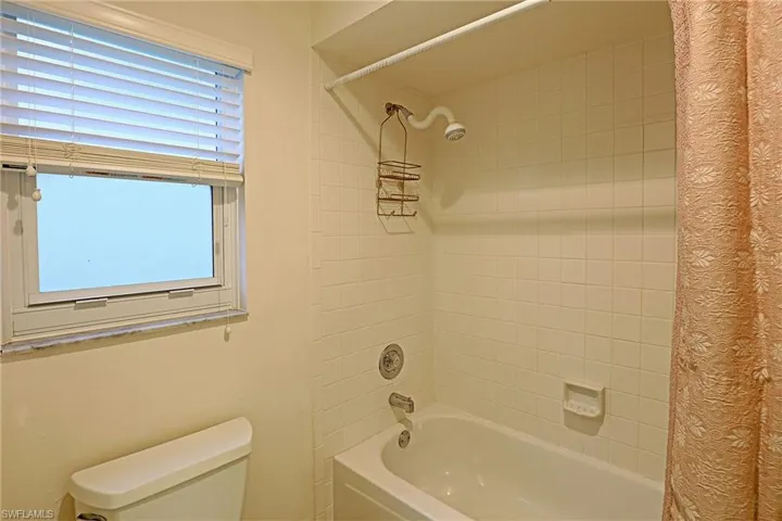 Full bathroom featuring toilet and shower / bath combination with curtain