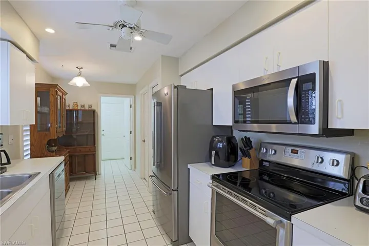 Kitchen featuring appliances with stainless steel finishes, light countertops, white cabinets, light tile patterned floors, and ceiling fan