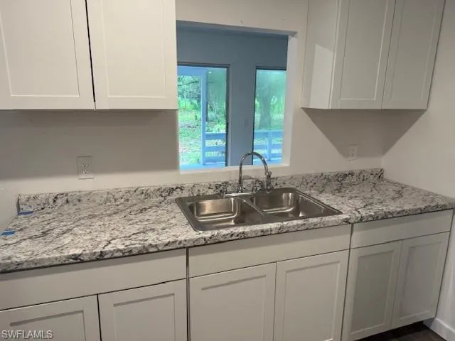 Kitchen featuring white cabinets and light stone counters