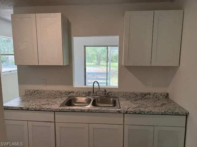Kitchen featuring white cabinetry, healthy amount of natural light, and a textured ceiling